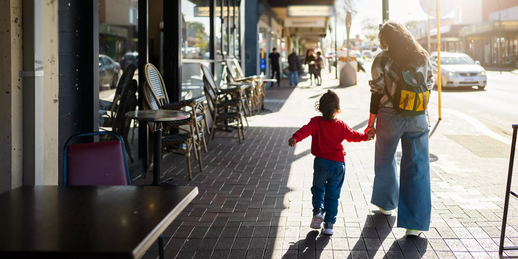 Mother and child holding hands walking down a street