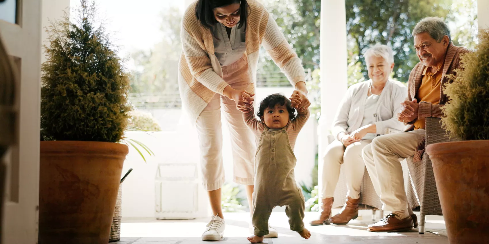 A mother walking a toddler with grandparents watching on